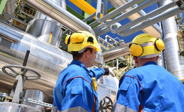 group of industrial workers in a refinery - oil processing equipment and machinery